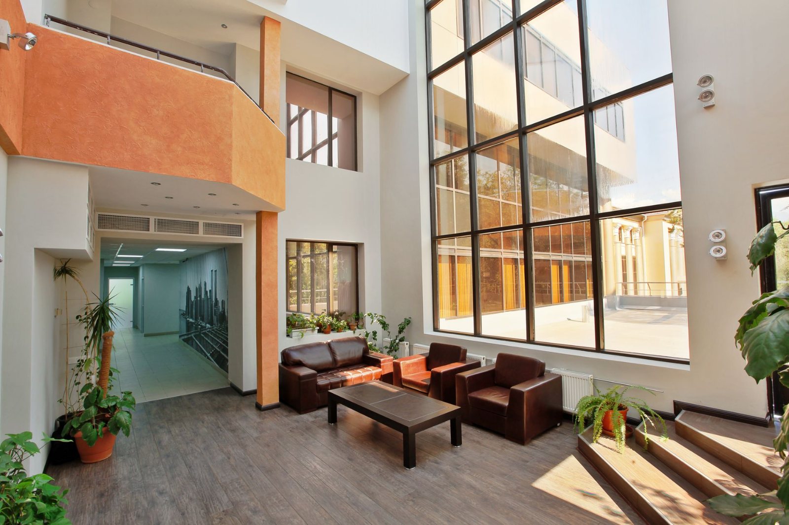 A small office lobby with clean low-pile carpet, chairs squared to a table, mail on the counter and a plant by the window